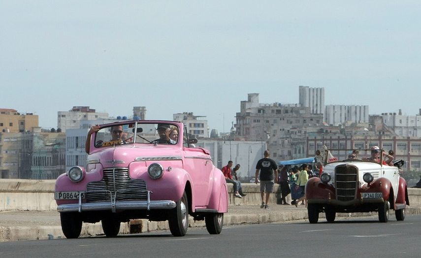 Fotografía del 26 de diciembre de 2014: varios turistas paseando por el malecón en dos autos antiguos en La Habana, Cuba. (EFE)