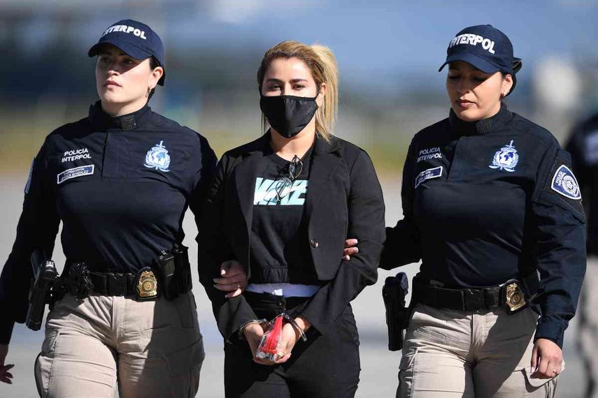 Nini Johana Usuga (C), hermana del narcotraficante Dairo Antonio Usuga, alias Otoniel, es escoltada por policías de Interpol antes de ser extraditada a EE. UU. en el Aeropuerto Internacional El Dorado, en Bogotá, Colombia, el 1 de julio de 2022.