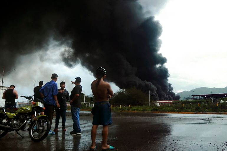 La gente mira el humo negro del incendio masivo en un depósito de combustible en una planta de refinación de petróleo de la estatal Petróleos de Venezuela (PDVSA) en Puerto La Cruz, estado de Anzoátegui, Venezuela  