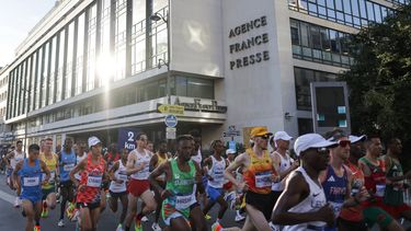 Atletas pasan por la sede de la Agence France Presse (AFP), en el maratón masculino de la prueba de atletismo de los Juegos Olímpicos de París 2024, en París, el 10 de agosto de 2024.