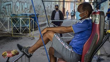 Un taxista en bicicleta espera a los clientes afuera de una puerta donde la policía controla el acceso a un vecindario en La Habana, Cuba, el lunes 22 de febrero de 2021.