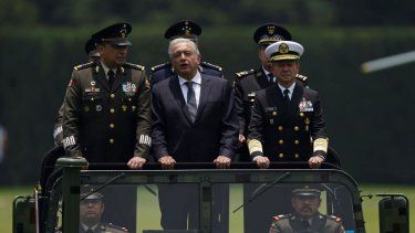 El presidente de México, Andrés Manuel López Obrador, en el centro; el secretario de Defensa, Luis Cresencio Sandoval, a la izquierda, y el comandante naval José Rafael Ojeda viajan en un vehículo militar durante un desfile de presentación del nuevo comandante del ejército, en Ciudad de México.