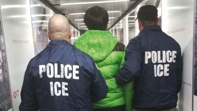 La autoridad policial de Inmigración ICE conduce a una persona a un avión para ser transportado a su país de origen.