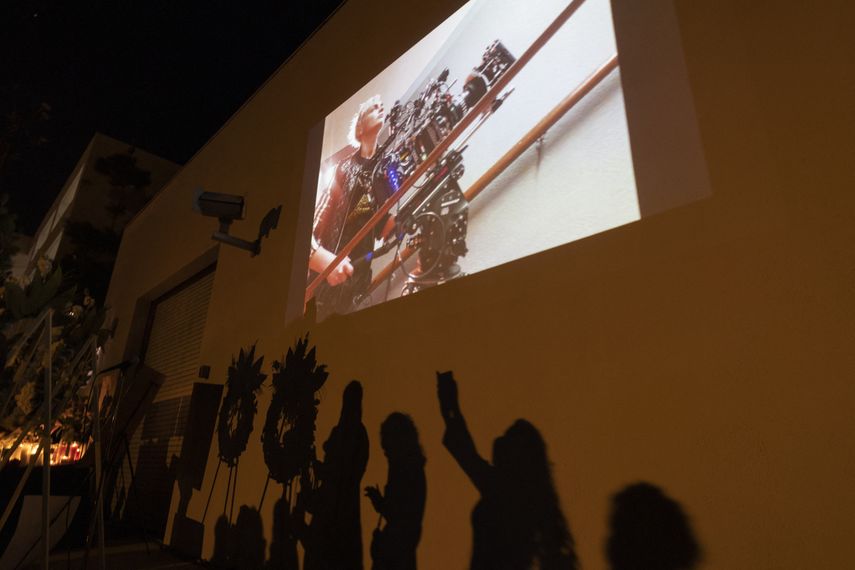 Una foto de la directora de fotografía Halyna Hutchins se ve sobre las sombras de las personas que se acercan a una mesa conmemorativa durante una vigilia con velas para Hutchins, quien fue asesinada accidentalmente por un arma de utilería disparada por el actor Alec Baldwin, en Burbank, California, el 24 de octubre de 2021.