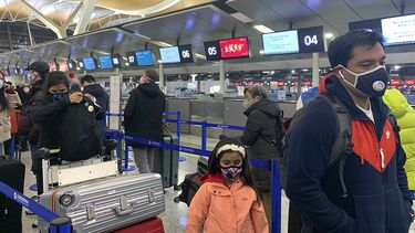 Viajeros con m&aacute;scaras hacen colan para registrarse en los mostradores de Cathay Pacific en el aeropuerto internacional de Shang&aacute;i, el jueves 30 de enero de 2020.