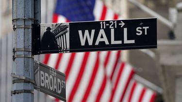 Imagen de la bandera de Estados Unidos detrás del letrero de la calle de Wall Street.