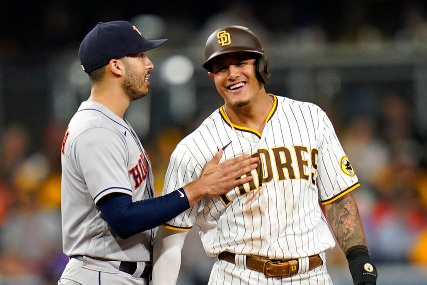 El campocorto de los Astros de Houston Carlos Correa (izquierda) bromea con Manny Machado, de los Padres de San Diego, en la segunda base en el séptimo inning del juego de la MLB que enfrentó a ambos equipos, el 3 de septiembre de 2021, en San Diego.