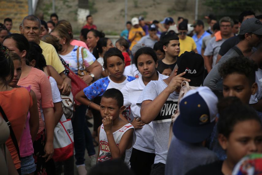 Migrantes de distintos países, incluyendo Honduras, Cuba, Venezuela y Nicaragua, hacen fila para recibir alimentos donados por voluntarios de Estados Unidos, al pie de un puente que cruza a Brownsville, Texas, en el centro de Matamoros, en el estado de Tamaulipas, México.&nbsp;
