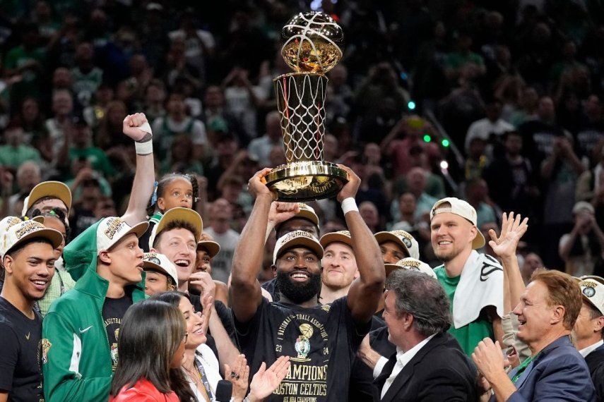 Jaylen Brown, centro, de los Celtics de Boston, alza el trofeo de campeonato Larry OBrien mientras celebra con su equipo la conquista del título de la NBA con una victoria en el Juego 5 de las Finales al superar a los Mavericks de Dallas, el lunes 17 de junio de 2024, en Boston.