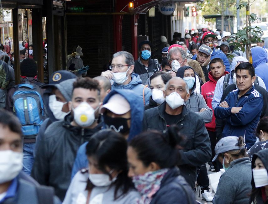 Cientos de personas usando m&aacute;scaras para protegerse del coronavirus COVID-19 hacen fila en Santiago de Chile, mientras esperan un seguro de empleo para los afectados por la pandemia.