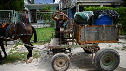 Un hombre se prepara para descargar agua de un bidón de plástico desde su carro tirado por caballos en La Habana, el 24 de septiembre de 2024.