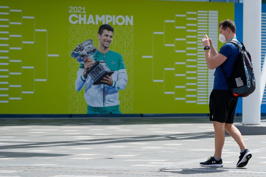 Aficionados sacan una foto frente a un cartel con la imagen del campeón defensor Novak Djokovic previo al Abierto de Australia en Melbourne Park, el martes 11 de enero de 2022