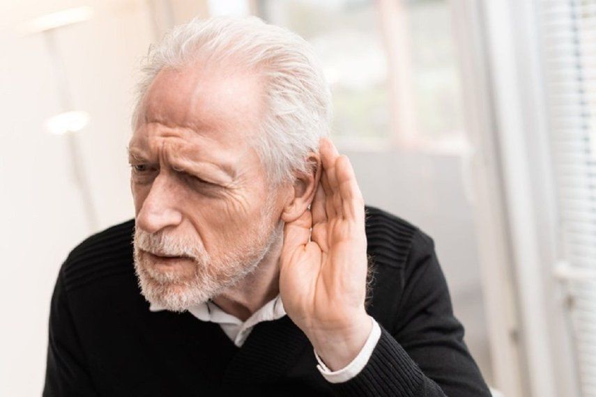 Hombre mayor con problemas auditivos intentaescuchar mejor haciendo un gesto con la mano.&nbsp;