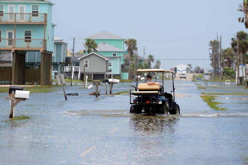 Jamie Baumgart conduce su carrito de golf por una calle inundada tras el paso de la tormenta tropical Alberto, en Surfside Beach, Texas, el jueves 20 de junio de 2024.