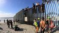 Decenas de migrantes centroamericanos llegan a la frontera México-Estados Unidos y trepan la valla que divide ambos países.