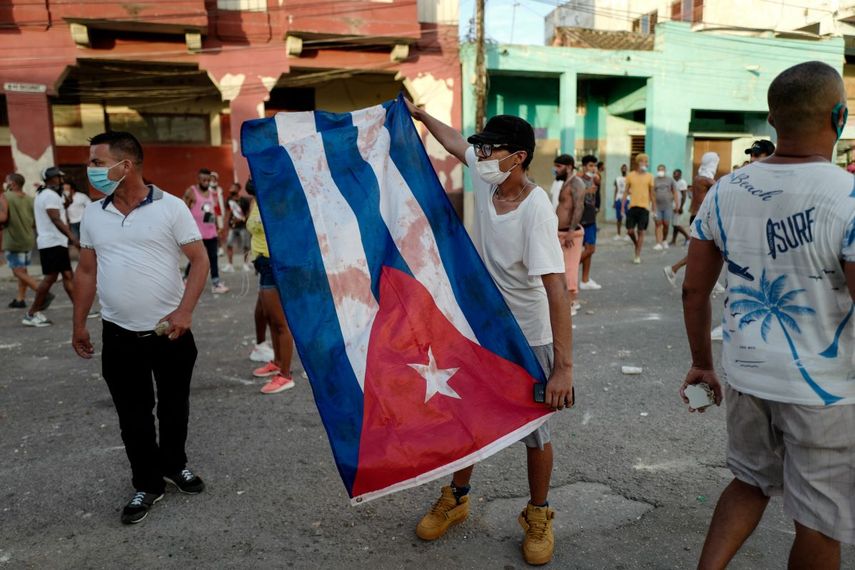 Un manifestante muestra la bandera cubana manchada de sangre durante el estallido social.