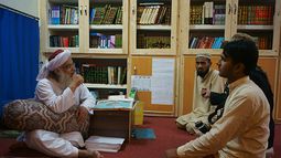 Maulana Abdul Aziz, el clérigo jefe de un paquistaní de seminario, charla con un visitante en una biblioteca que lleva el nombre de asesinado líder de Al Qaeda, Osama Bin Laden. (AP)