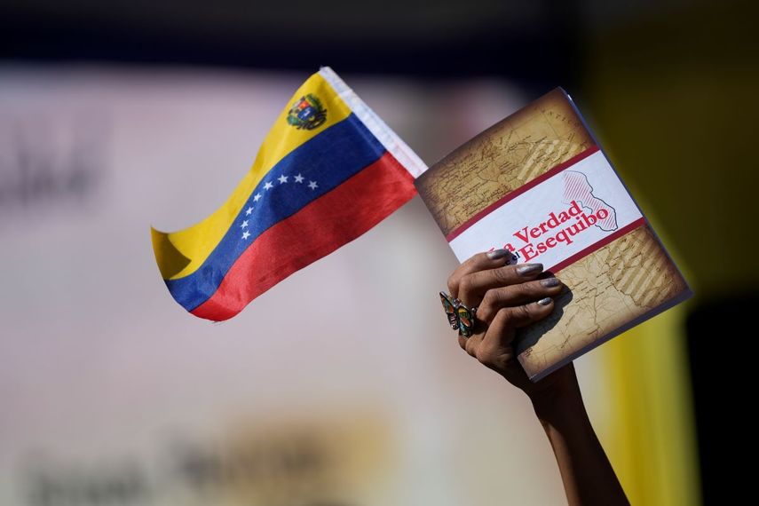 Una mujer sostiene una bandera venezolana y un libro sobre la disputa del territorio de Esequibo en Caracas, el miércoles 29 de noviembre de 2023.