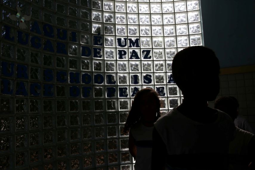 Niños que se dirigen a almorzar mientras se observa a sus espaldas un pedido de paz en su escuela en Río de Janeiro (Brasil). &nbsp;