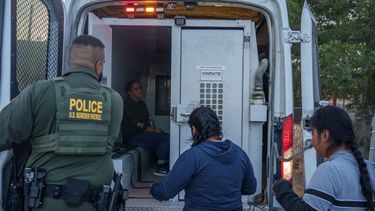 Un agente de Inmigración traslada a inmigrantes detenidos.