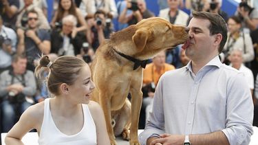 La actriz Zsofia Psotta, izquierda, mira al director Kornél Mndruczó mientras lo besa un perro durante una sesion de fotos para la película White Dog. (AP)