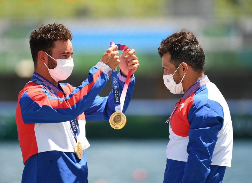 El medallista de oro de Cuba Serguey Torres Madrigal (der.) recibe la medalla de manos de su compañero de equipo Fernando Dayan Jorge Enríquez durante los Juegos Olímpicos de Tokio 2020