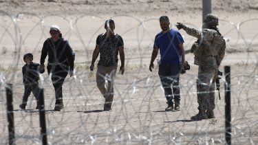 Migrantes esperan a las autoridades estadounidenses en la frontera entre EEUU y México, visto desde Ciudad Juárez, México.