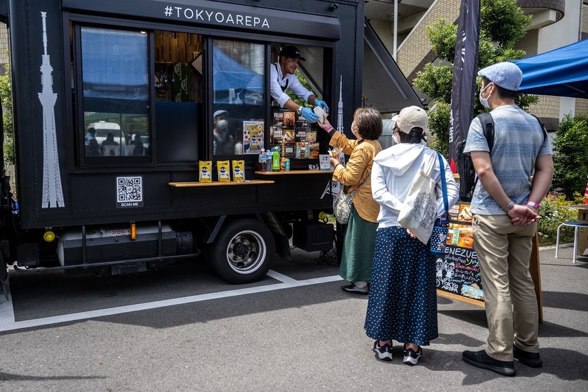 El venezolano Raúl Márquez (centro) vende arepas, un popular platillo sudamericano hecho con harina de maíz, desde su camión de comida durante un evento en un mercado de agricultores en Ichikawa, prefectura de Chiba, un suburbio al este de Tokio, el 27 de mayo de 2023. De Caracas a Nueva York, pasando por París, Tokio y Hong Kong, en puestos callejeros y restaurantes gourmet... La arepa, plato venezolano a base de maíz, conquista el mundo gracias a una ola migratoria y al creciente mercado sin gluten . &nbsp; Felipe FONG / AFP