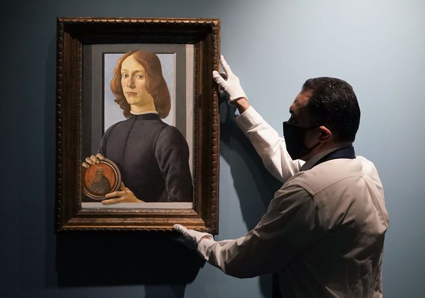 En esta foto de archivo tomada el 27 de enero de 2021, un manipulador de arte de Sotheby’s arregla El joven sosteniendo un Roundel de Botticelli durante una vista previa para la prensa en Sotheby’s, en Nueva York. El retrato se vendió por 92 millones de dólares, cifra récord para el artista.