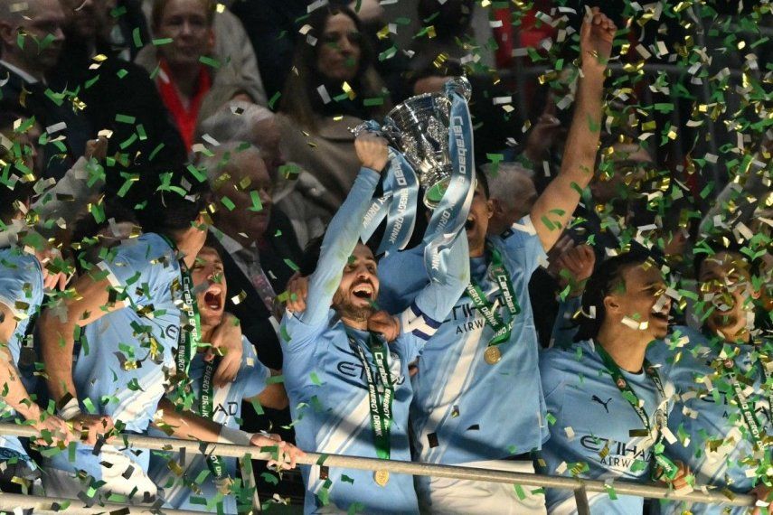 El centrocampista portugués del Manchester City, Bernardo Silva, número 20, levanta el trofeo mientras los jugadores del City celebran tras la final de la Copa de la Liga inglesa entre el Arsenal y el Manchester City en el estadio de Wembley en Londres el 22 de marzo de 2026. El City ganó el partido 2-0.