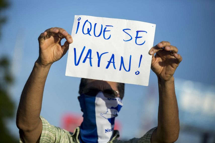 Ciudadano levanta un cartel en contra del gobierno de Daniel Ortega.&nbsp;
