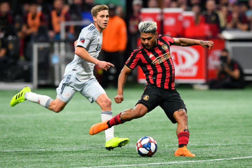 El atacante venezolano Josef Martínez del Atlanta United remata a puerta ante el volante Scott Caldwell del New England Revolution en los playoffs de la MLS, el 19 de octubre de 2019.