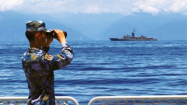 Militar chino observa la costa de Taiwán a bordo de un buque de guerra.