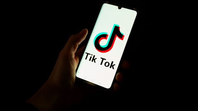 Esta fotografía tomada el 19 de abril de 2024 muestra a un hombre sosteniendo un teléfono inteligente que muestra el logotipo de la plataforma de redes sociales china Tiktok en una oficina en París.