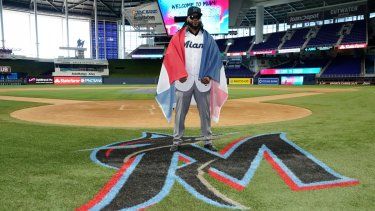 El dominicano Johnny Cueto posa para una foto, envuelto en la bandera de su país y con el jersey de los Marlins de Miami, el jueves 19 de enero de 2023.