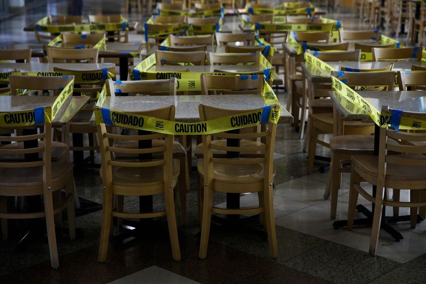 Un precinto de cinta amarilla rodea mesas y sillas en una zona de restaurantes para evitar que se usen los comedores interiores durante la pandemia del coronavirus, en Koreatown, Los Ángeles, el 8 de julio de 2020.