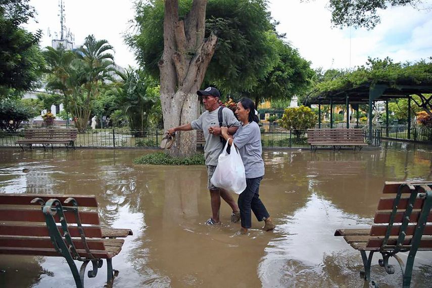 Pareja caminando en la inundada Plaza de Armas de la ciudad de Piura, a unos 1000 kilómetros al norte de Lima.