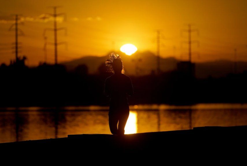 Una deportista corre al lado del lago Tempe Town al amanecer del miércoles 12 de julio de 2023, en Tempe, Arizona. 