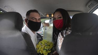 Ayrton (izquierda) y Natasha, con mascarillas para protegerse del coronavirus, posan para un fotograf&iacute;a tras casarse en un drive-thru en un registro del vecindario de Santa Cruz, en R&iacute;o de Janeiro, Brasil, el 28 de mayo de 2020.&nbsp;