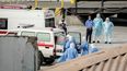 Personal sanitario que regresa del crucero MV Hondius es visto en el puerto de Praia, la capital de Cabo Verde, mientras se ayuda a subir a una ambulancia a personas que visten trajes de protección biológica, el 6 de mayo de 2026.