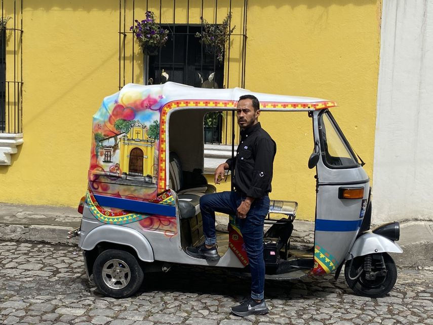 René Hugo Castillo en su tuc tuc -un pequeño vehículo fabricado en La India utilizado para transportar turistas- por las calles de Antigua en Guatemala