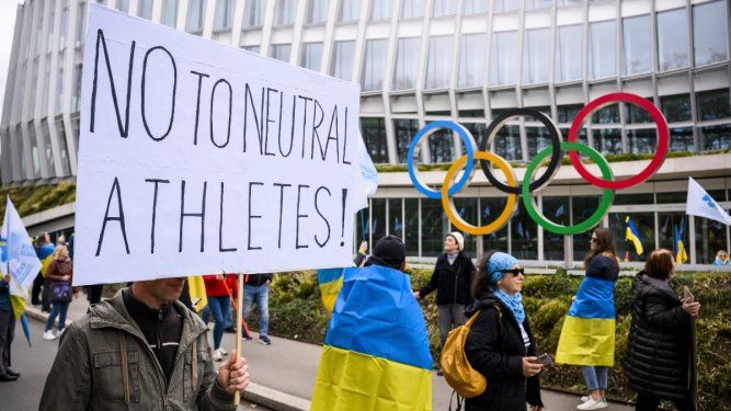 Miembros de la comunidad ucraniana en Ginebra, Suiza, protestan durante una marcha para pedir al Comité Olímpico Internacional que reconsidere su decisión sobre la participación de deportistas rusos y bielorrusos bajo una bandera neutral para los próximos Juegos Olímpicos de París 2024, frente a la sede del COI, el sábado 25 de marzo de 2023.