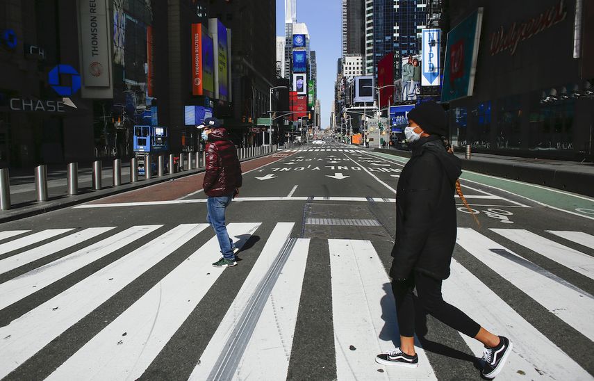 La gente usa una m&aacute;scara facial mientras cruzan una calle en Times Square el 22 de marzo de 2020 en la ciudad de Nueva York.&nbsp;&nbsp;