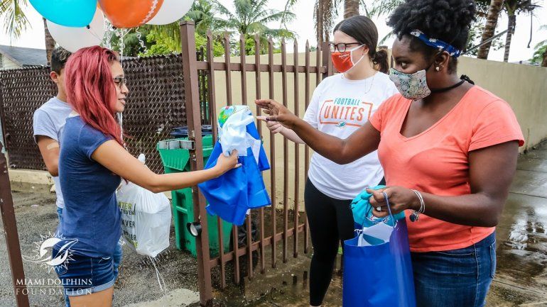 Los Dolphins entregan regalos a Sacha, la novia del joven Brayan (detrás, en la foto), como parte de su labor social en el Mes de la Herencia Hispana.
