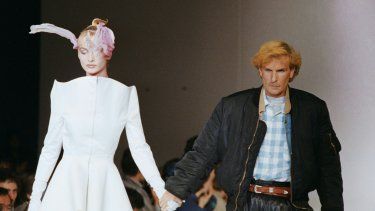 El diseñador francés Claude Montana saluda al público con una modelo luciendo su creación al final de su desfile de moda prêt-à-porter primavera-verano en París el 17 de octubre de 1987.