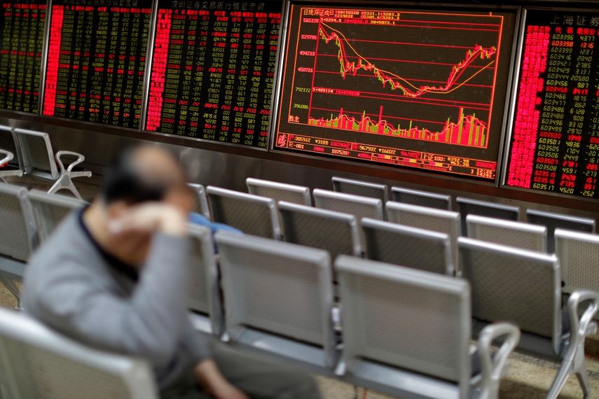 Un hombre descansa, este miércoles, junto a un panel que muestra la evolución de la bolsa de Shanghái en Pekín (China).&nbsp;