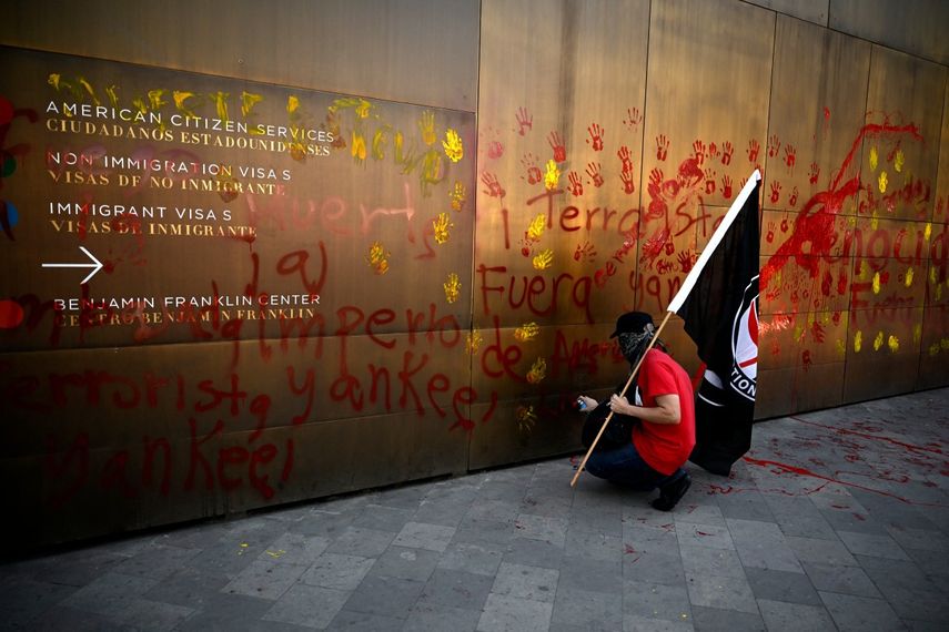 Un miembro de una organización social realiza un grafiti en el muro de la embajada estadounidense como protesta contra la operación militar estadounidense en Venezuela, en la Ciudad de México, el 3 de enero de 2026.