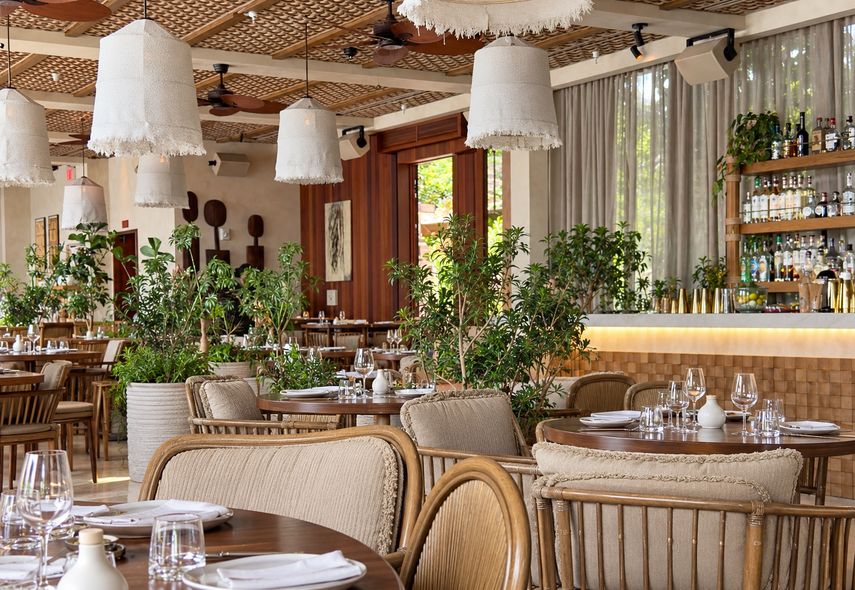 La decoración del salón principal de Casa NEOS combina madera, vegetación y lámparas de fibras naturales.