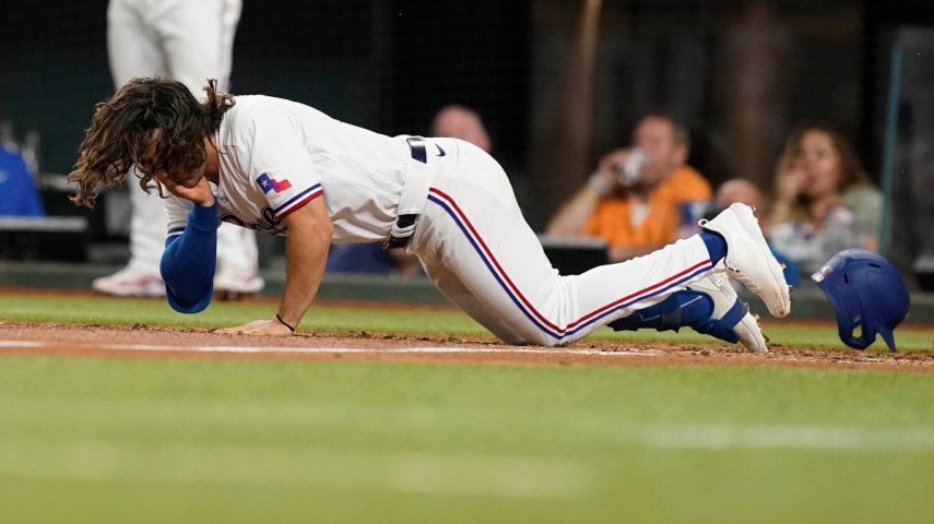 Josh Smith, de los Rangers de Texas, cae después de haber sido golpeado en la cara por un lanzamiento durante la tercera entrada del juego de béisbol en contra de los Orioles de Baltimore, en Arlington, Texas, el lunes 3 de abril de 2023.&nbsp;