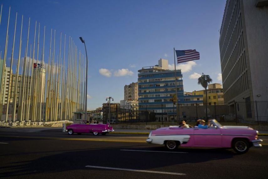 Turistas montando en autos descapotables clásicos junto a la embajada de Estados Unidos en Cuba